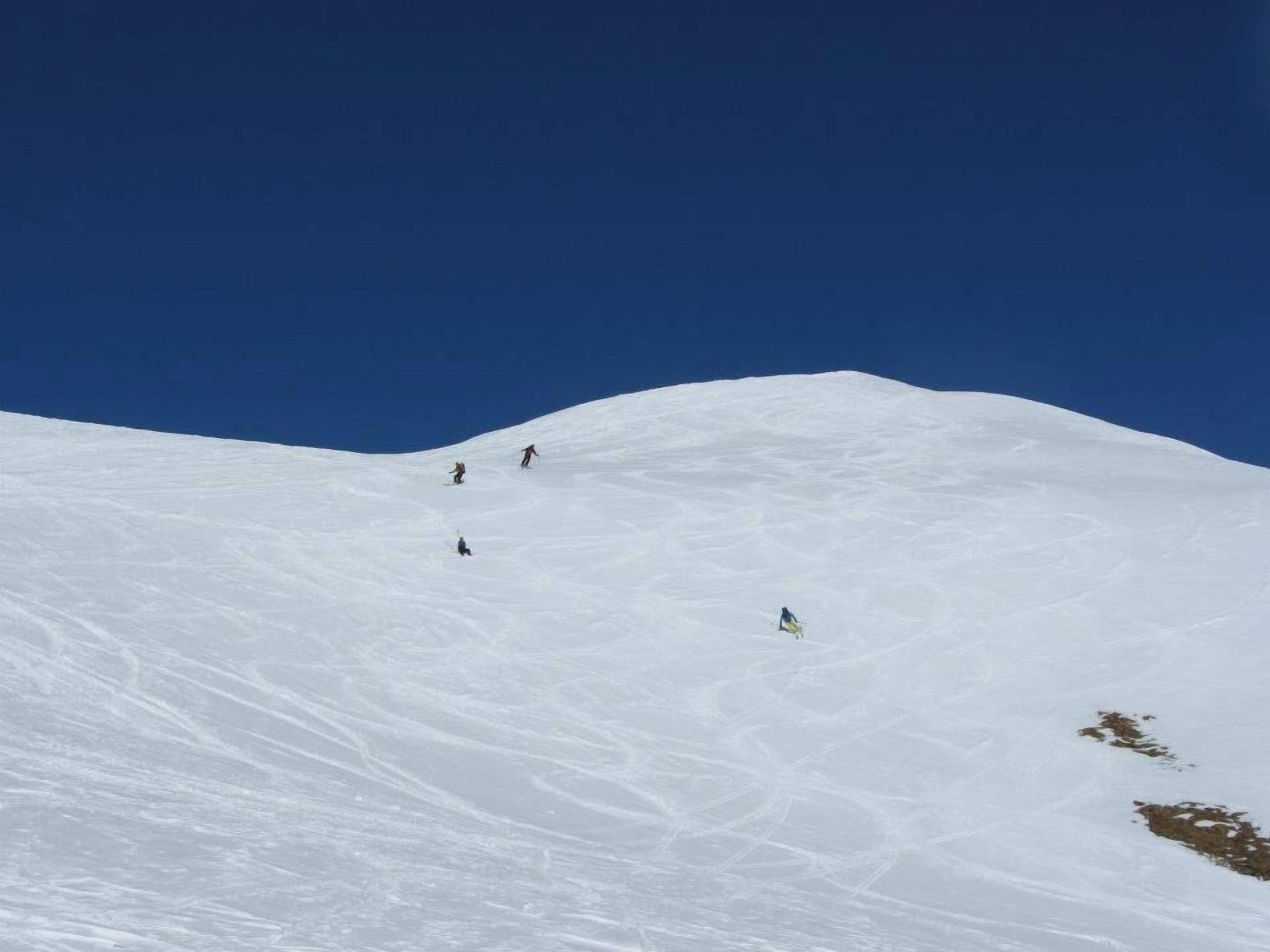 Une pente de montagne enneigée où l’on voit des skieurs.