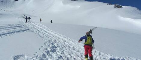 A snowy mountain path with skiers ascending.