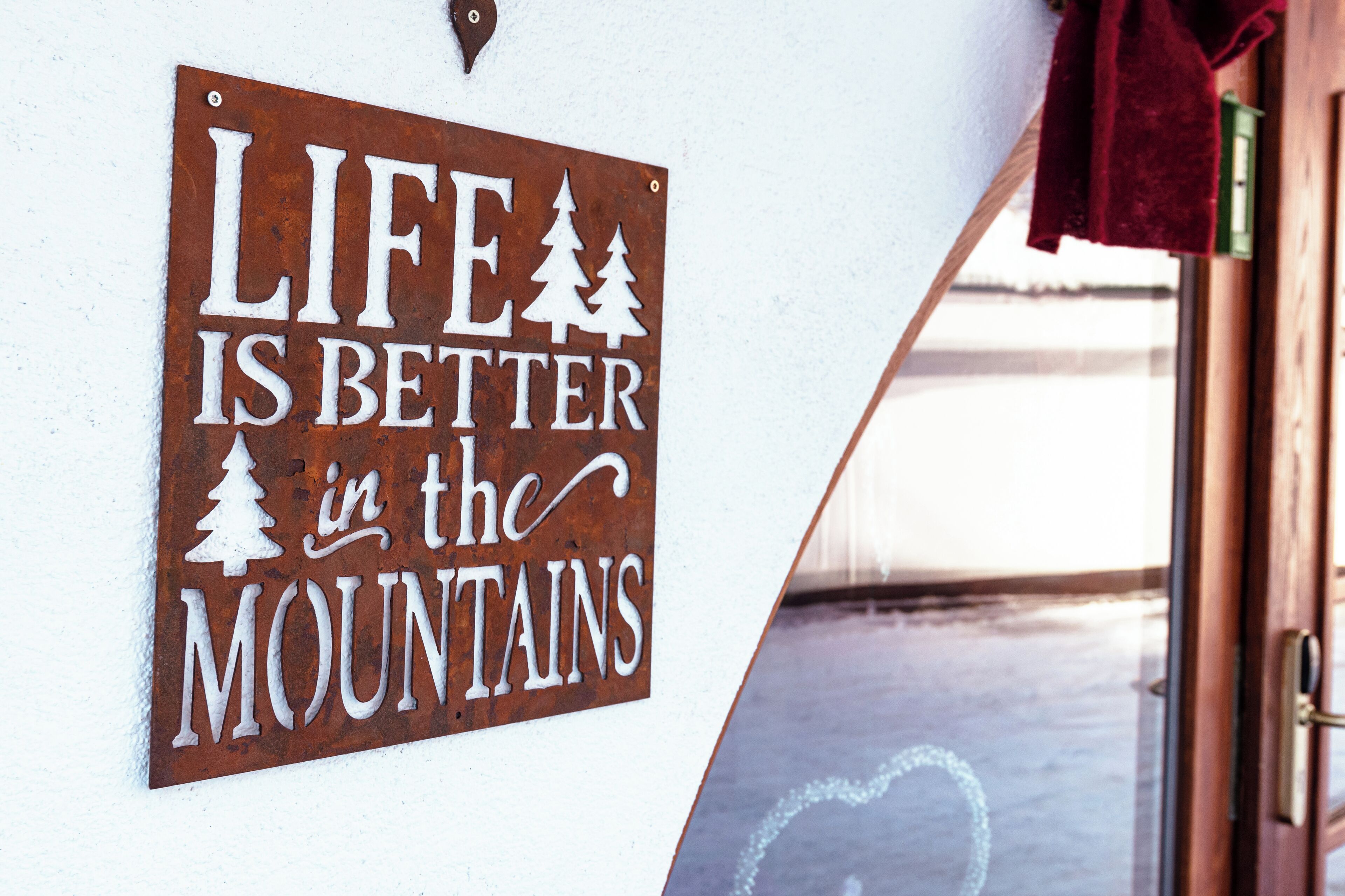 A sign with the text "LIFE IS BETTER in the MOUNTAINS" mounted on a wall.