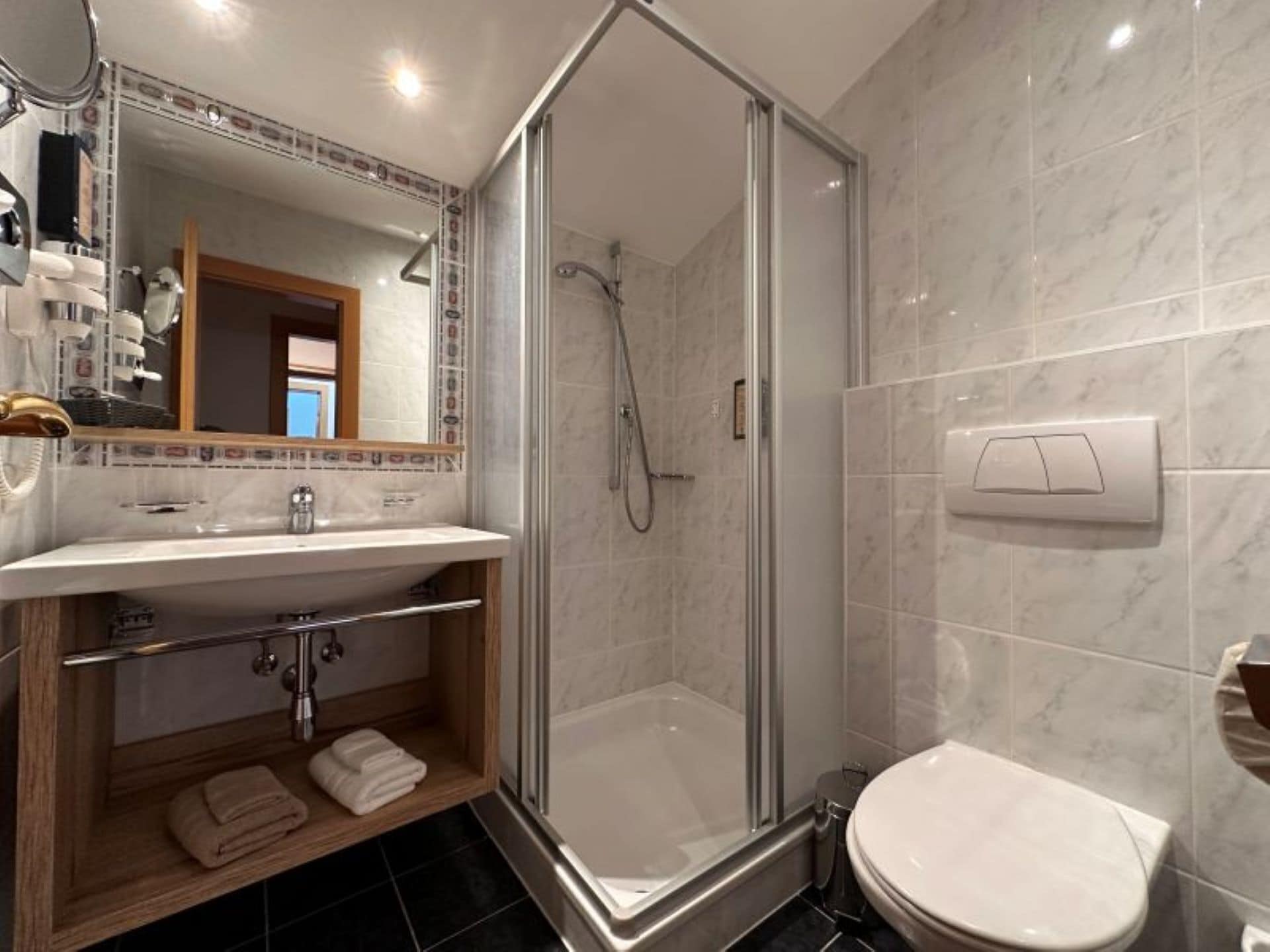 A modern bathroom with a glass-enclosed shower, a sink with a towel rack, and a toilet.