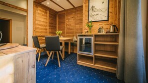 A wooden interior with a dining area, a small kitchenette, and a framed artwork on the wall. - Arlen Lodge Hotel (Sankt Anton am Arlberg)