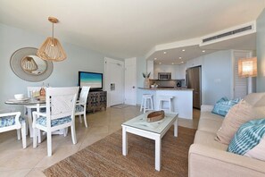 Een moderne woonkamer met een eethoek, keuken en een grote televisie.