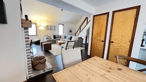Un salón espacioso con una mesa de comedor de madera, un juego de sofá gris y una escalera que lleva a otro nivel.