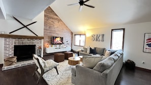 Una sala de estar acogedora con chimenea, un televisor grande y un sofá.