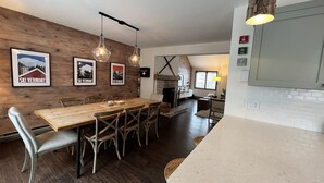 A dining area with a wooden table and chairs, a fireplace, and framed pictures on the wall. - Basecamp Mount Snow + Modern & Perfect for 2 families + 5 min. to ski mountain!  (Dover)
