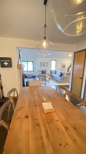 Una mesa de comedor de madera con sillas, una lámpara colgante y un cartel con la palabra “SKI” en la pared.