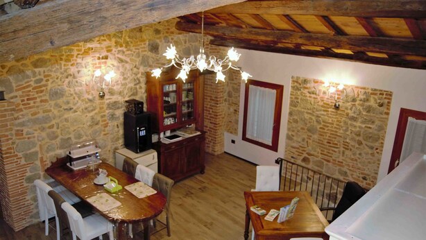 A rustic dining area with stone walls, wooden furniture, and a chandelier. - B&B Tito Livio (Teolo)