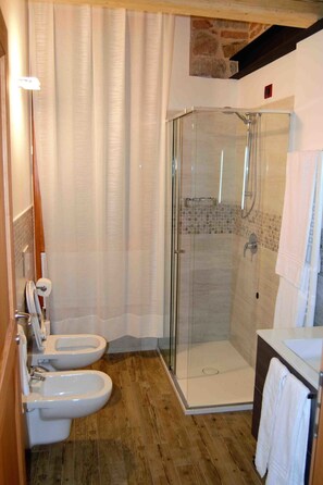 A modern bathroom with a glass-enclosed shower, two toilets, and a sink. - B&B Tito Livio (Teolo)