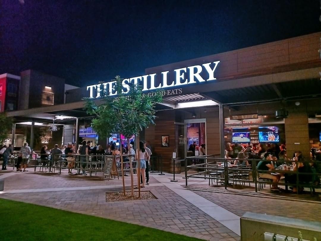 A restaurant named 'The Stillery' with outdoor seating and a sign above the entrance.