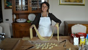 Une cuisine avec une table en bois, un rouleau à pâtisserie et un saladier rempli de pâte.