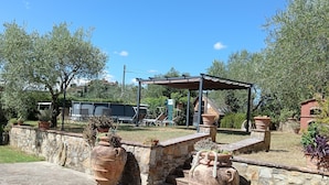 Une cour dallée de pierres, avec des sièges extérieurs et de grands pots en terre cuite.