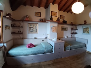 Una habitación acogedora con dos camas, vigas de madera en el techo y estantes con diversos objetos.