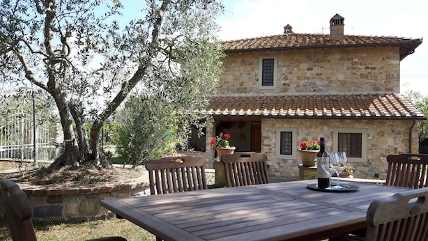 Un bâtiment en pierre avec un toit en tuiles, une table en bois et des chaises.