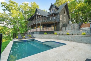 A two-story house with a swimming pool, outdoor seating, and a stone retaining wall. - Huckleberry Hideout by SoCharm | Private Cabin Oasis (Mooresville)