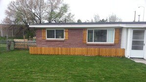 A single-story house with a brick facade, two windows with shutters, and a wooden fence in front. - Skiing, Mt Biking, Climbing, Hiking, Boating, Swimming, ATV Trails. (Bountiful)