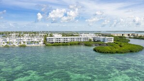 Un port de plaisance avec des bateaux, un grand bâtiment d’hôtel et une petite île couverte d’une végétation luxuriante.