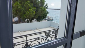 A balcony with a metal railing, a tree, and a view of the sea. - Panellinion Luxury Rooms (Kalamata)