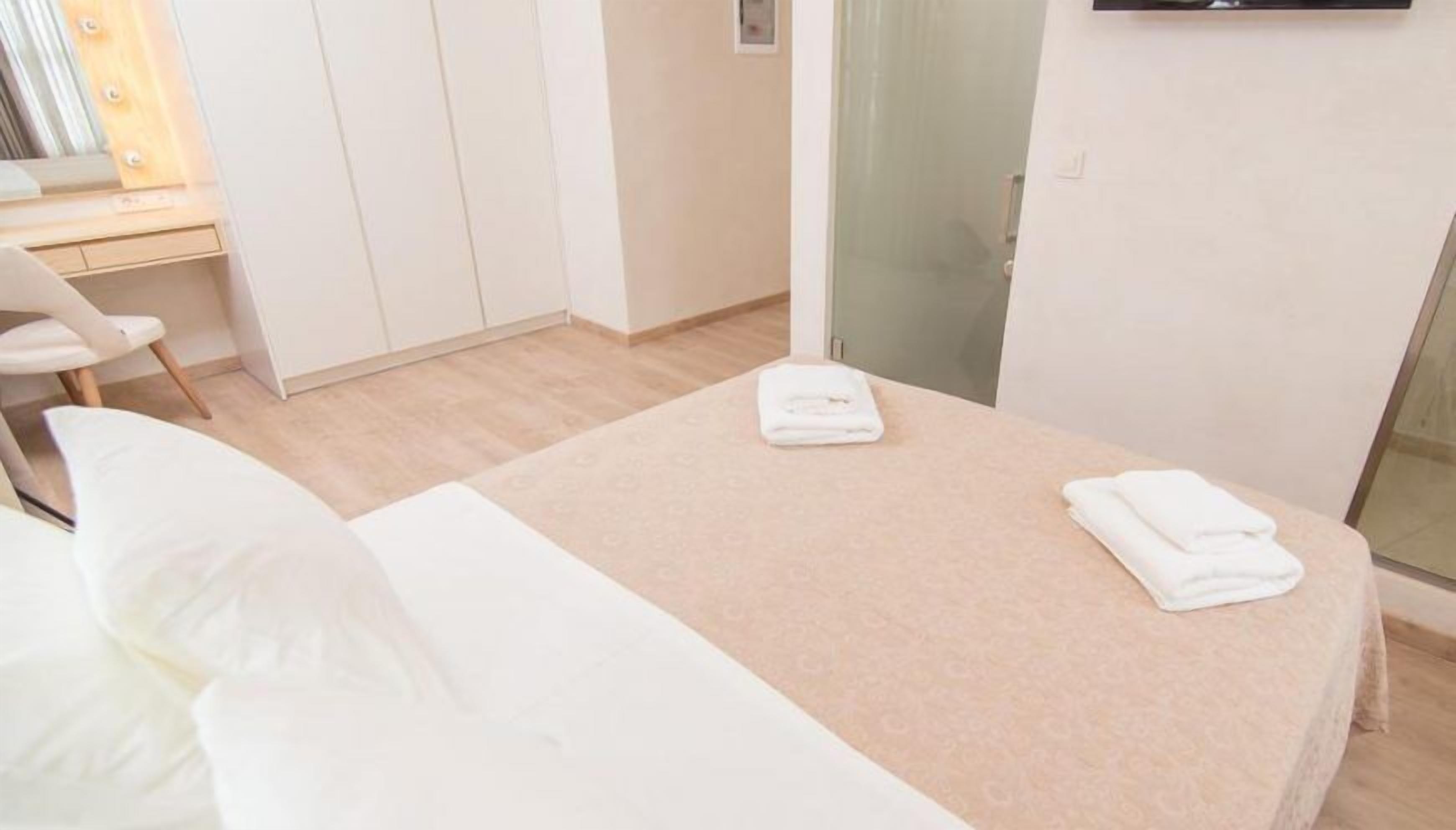 Ein ordentlich eingerichtetes Schlafzimmer mit Bett, Stuhl, Schreibtisch und Kleiderschrank.