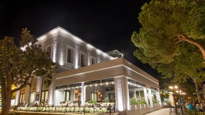 A modern hotel with a spacious outdoor seating area, large windows, and a well-lit entrance. - Panellinion Luxury Rooms (Kalamata)