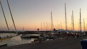 A marina with multiple sailboats docked, a small building, and a few people walking. - Panellinion Luxury Rooms (Kalamata)