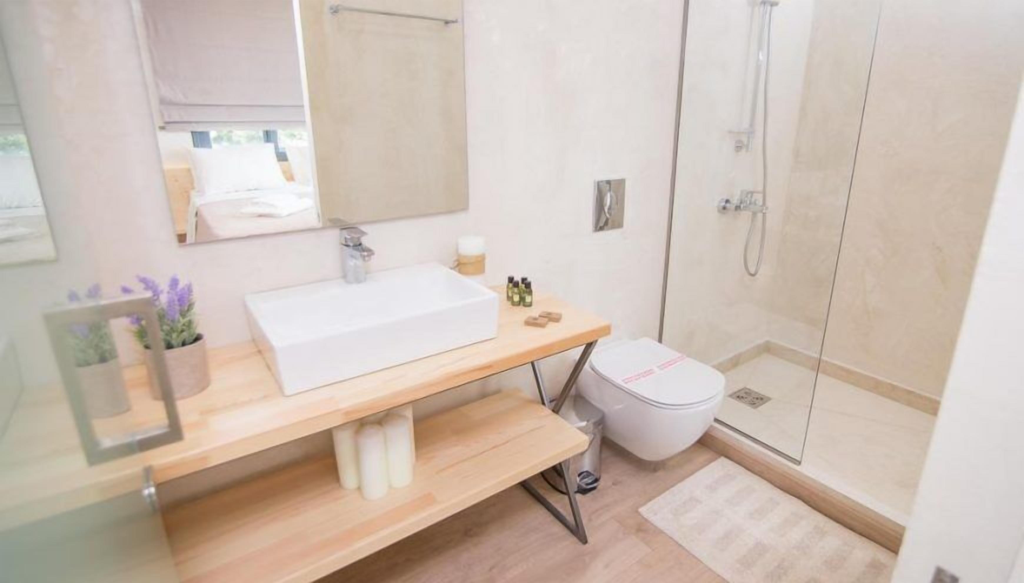 Un bagno moderno con lavandino, specchio e doccia bianchi.