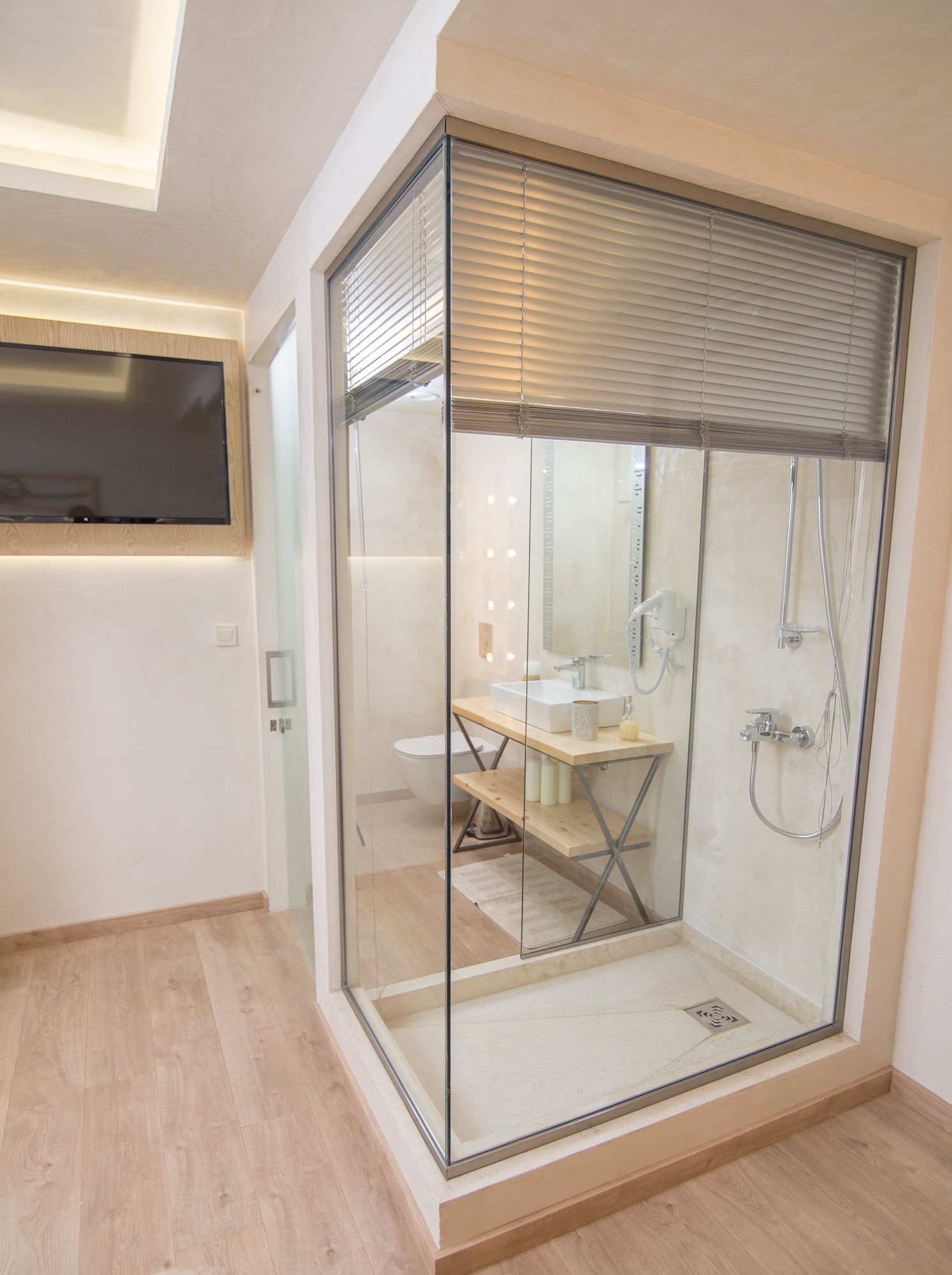 Un baño moderno con cabina de ducha de vidrio, tocador de madera y un inodoro.