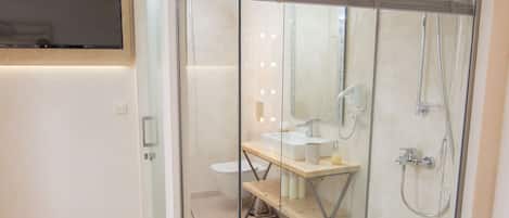 Un baño moderno con cabina de ducha de vidrio, tocador de madera y un inodoro.