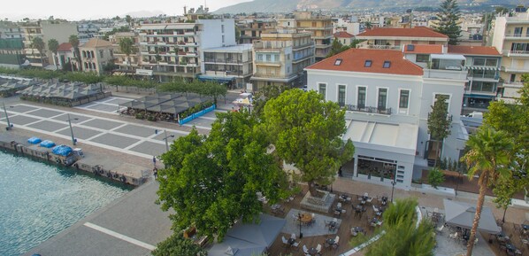 A coastal hotel with outdoor seating, a pool, and a view of the cityscape. - Panellinion Luxury Rooms (Kalamata)
