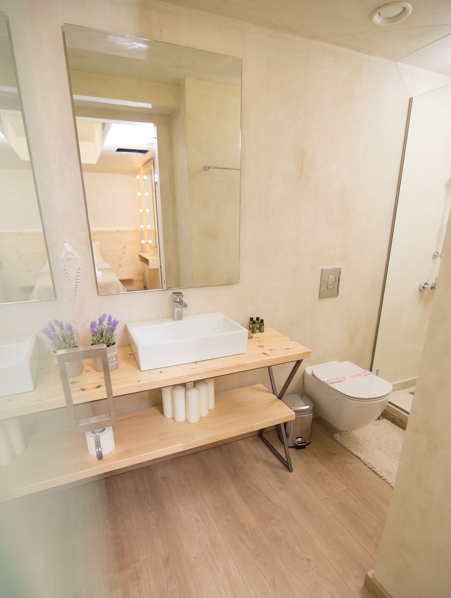 Een moderne badkamer met een glazen wastafel, een grote spiegel en een douche.