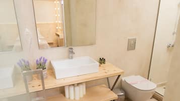 Een moderne badkamer met een glazen wastafel, een grote spiegel en een douche.