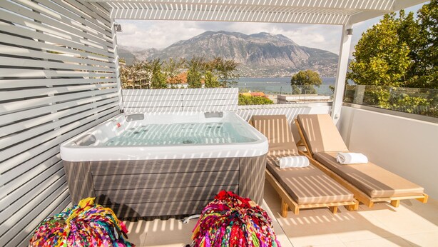 A rooftop terrace with a hot tub, lounge chairs, and colorful umbrellas. - Panellinion Luxury Rooms (Kalamata)