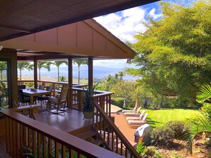 A covered outdoor area with a wooden deck, a table with chairs, and a view of the ocean. - Wailea Custom Home, Pool, Panoramic Ocean View, Waterfalls - Maui Ocean Palms (Kihei)