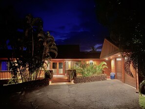 A two-story building with a front entrance, a driveway, and a well-maintained garden with various plants. - Wailea Custom Home, Pool, Panoramic Ocean View, Waterfalls - Maui Ocean Palms (Kihei)