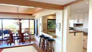 A modern kitchen with white cabinets, a wooden countertop, and a bar area with stools.