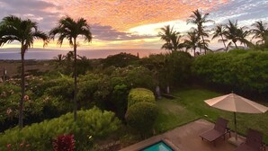 A pool with a view of the sunset and palm trees.