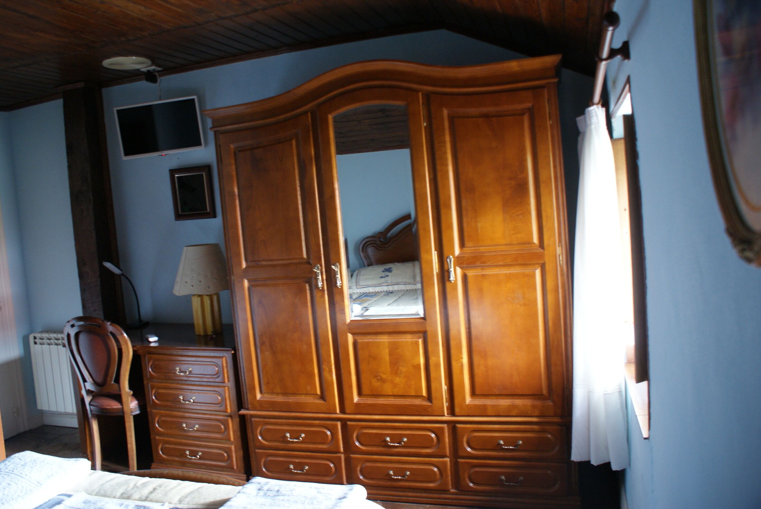 Ein Schlafzimmer mit einem Holfischschrank, einem Schreibtisch und einem Stuhl.