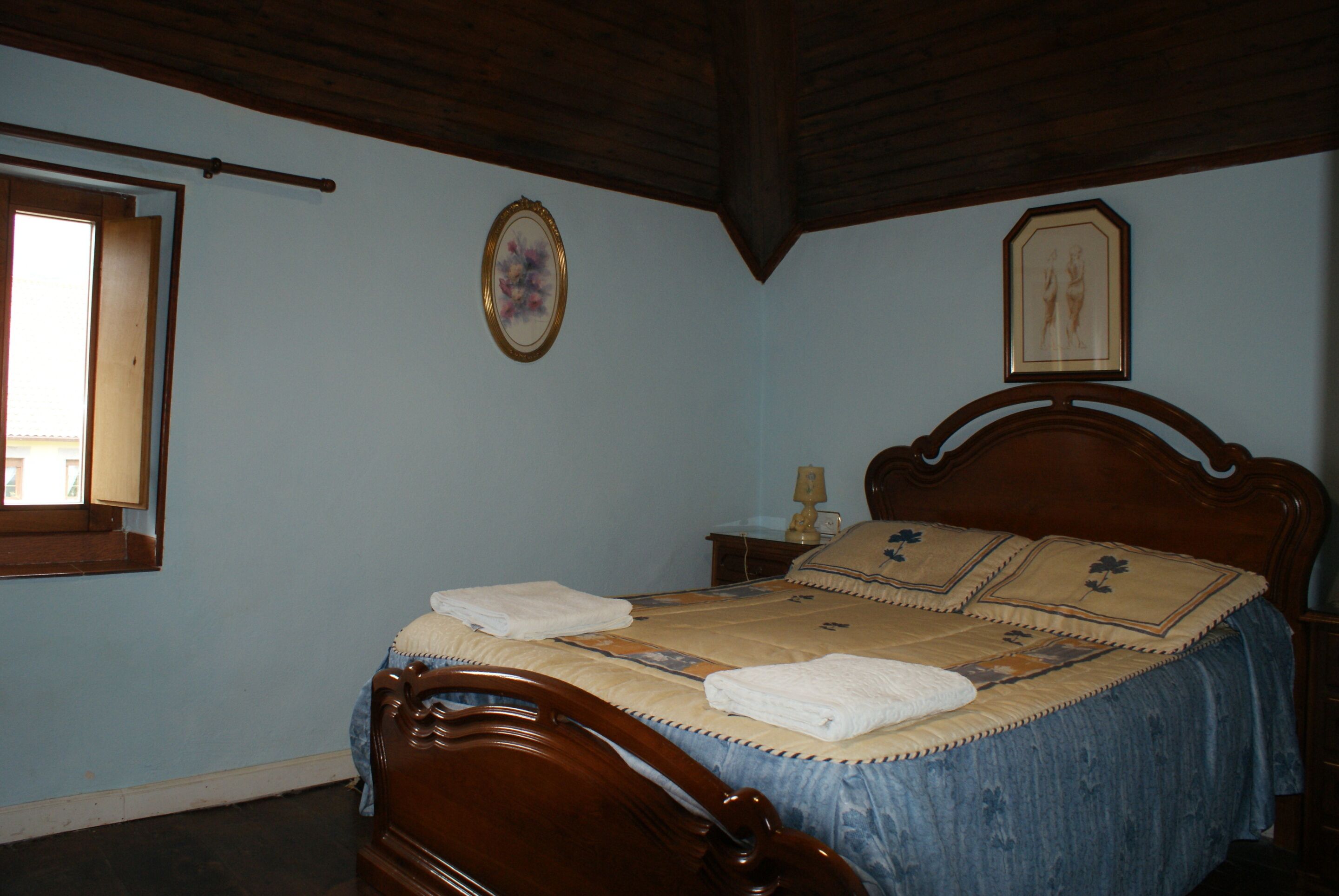 Une chambre à coucher avec un lit en bois, une table de chevet et une fenêtre.