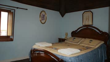 Un dormitorio con cama de madera, una mesita de noche y un ventanal.