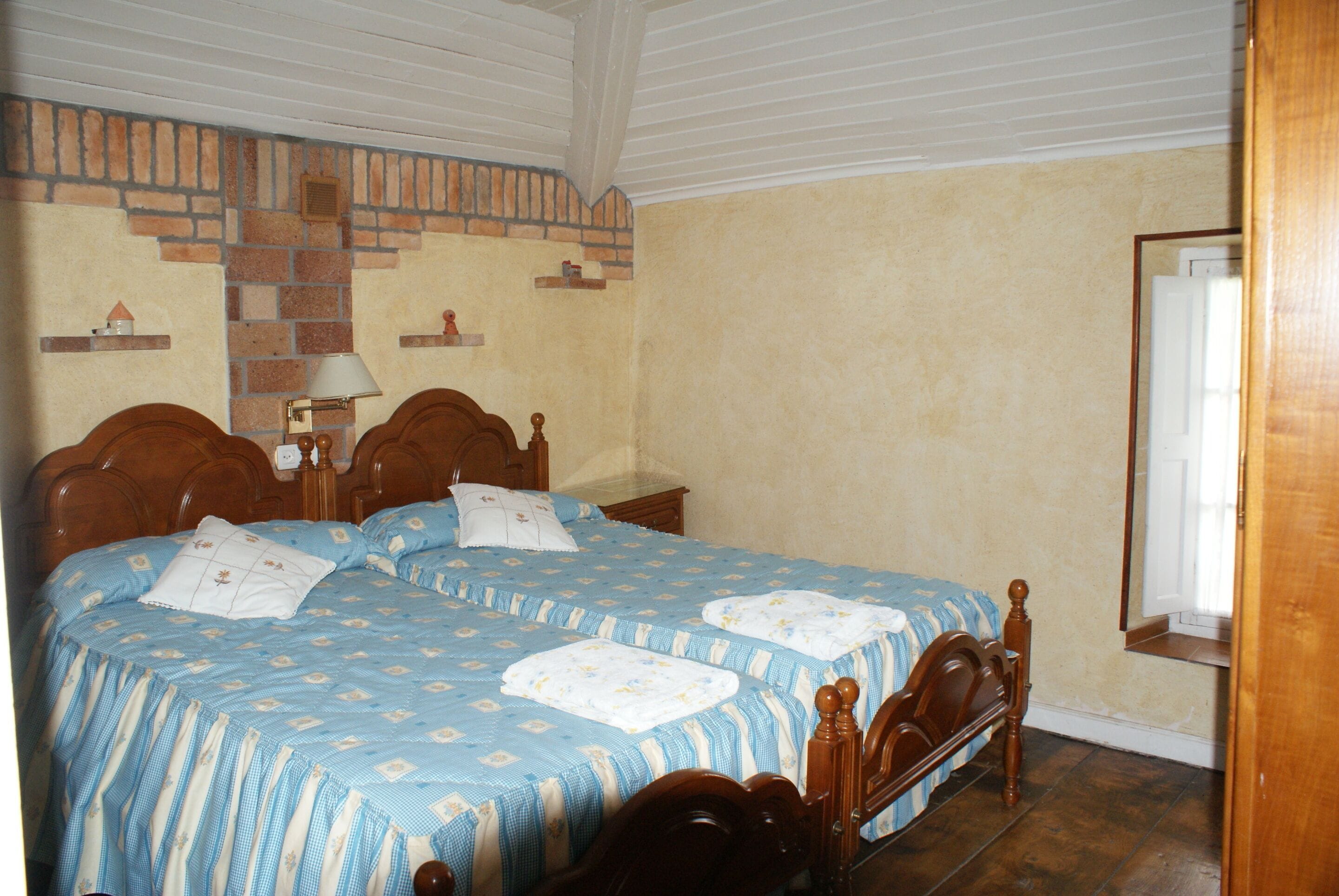 Un dormitorio con dos camas de madera, una pared con diseño de ladrillo y un espejo.