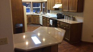 A kitchen with wooden cabinets, a granite countertop, and a black stove. - Secluded large home. Wooded setting. Easy commute to downtown.  (Portland)