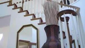 A staircase with white balusters and wooden steps, a large mirror, and a tall vase with dried plants. - Secluded large home. Wooded setting. Easy commute to downtown.  (Portland)