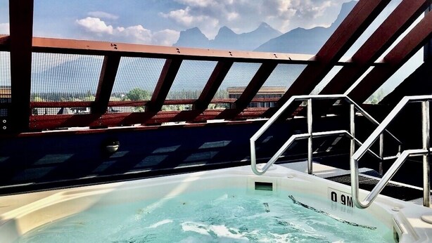 Un bain à remous avec vue sur les montagnes, une rambarde et un ciel dégagé.