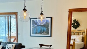 Un coin repas avec une table et des bancs en bois, un tableau encadré au mur et un lit avec une tête de lit en bois.