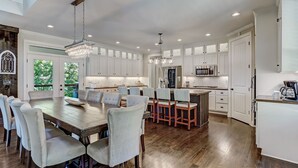 A spacious kitchen with white cabinetry, a large dining table, and multiple light fixtures. - Executive Retreats, Family Reunions, Near Montaluce, 8 King Beds  (Dahlonega)