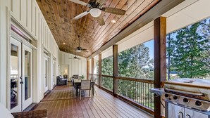 A covered deck with wooden flooring, ceiling fans, a grill, and a dining area with chairs and a table. - Executive Retreats, Family Reunions, Near Montaluce, 8 King Beds  (Dahlonega)