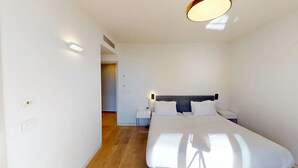 Une chambre d’hôtel moderne avec un grand lit, des tables de chevet et un luminaire au plafond.
