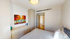 A bedroom with a bed, a dresser, a painting, and a door leading to another room.