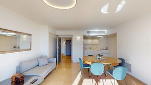 Un salon moderne comprenant un canapé, une table à manger avec des chaises, un coin cuisine et un couloir.