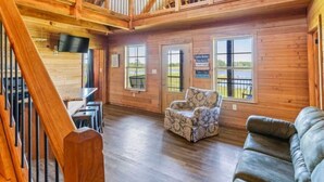 A spacious wooden interior with a high ceiling, a staircase, a sofa, and a patterned armchair. - Rural Respite & Retreat Area (Fitzpatrick)