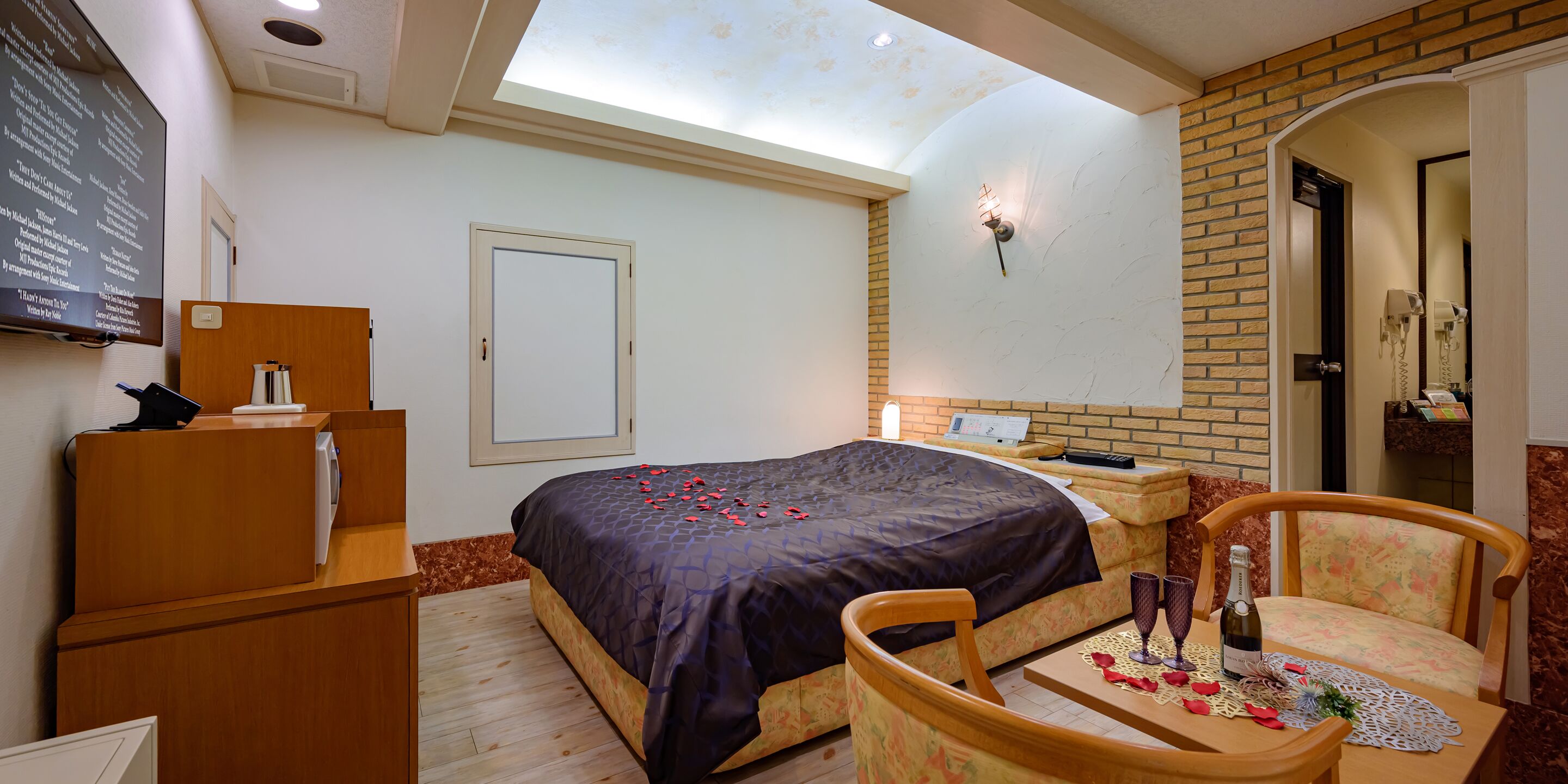 Une chambre à coucher comprenant un lit, un bureau, une chaise, une table de chevet, un miroir, une porte et une fenêtre de toit.